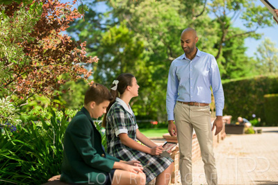 January 2024 / Teacher-Standing-with-2-Studenst-Sitting-Outdoors_240122_Z9E8457