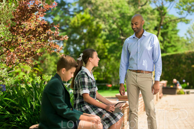 January 2024 / Teacher-Standing-with-2-Studenst-Sitting-Outdoors_240122_Z9E8461