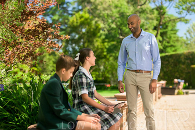 January 2024 / Teacher-Standing-with-2-Studenst-Sitting-Outdoors_240122_Z9E8481