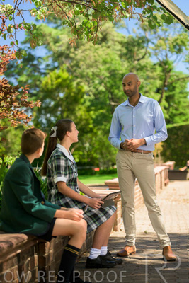 January 2024 / Teacher-Standing-with-2-Studenst-Sitting-Outdoors_240122_Z9E8539