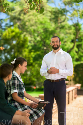 January 2024 / Teacher-Standing-with-2-Studenst-Sitting-Outdoors_240122_Z9E8641